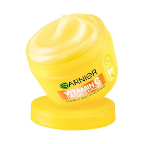 Geöffneter gelber Cremetiegel Garnier Vitamin C Fresh & Bright, schräg vor weißem Hintergrund